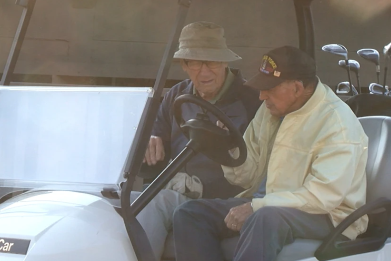 two elderly men in a golf cart